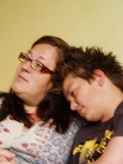 A boy with dark hair rests his head on his mother's shoulder